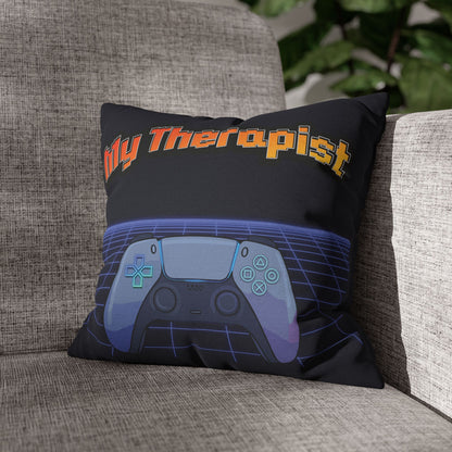 A square throw pillow resting on a gray fabric sofa. The pillow is black with the text 'My Therapist' in orange and yellow, above a stylized video game controller graphic in shades of blue, purple, and gray.